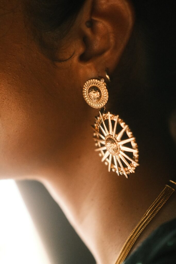 A close up of a person wearing a pair of earrings, Goldschmuck